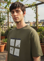 Man wearing a green t-shirt with 'Skate & Glory' graphic design outdoors.